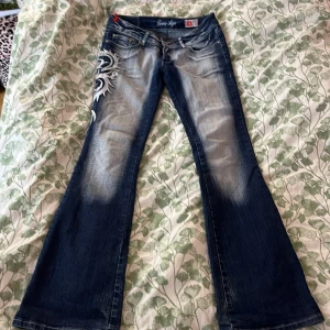 Teen age jeans  - Snygga teen age jeans med en unik design på sidan. De är bootcut och är lågmidjade. Innerbenslängden är 84cm och midjemåttet 38cm, skriv för bilder eller frågor 💕