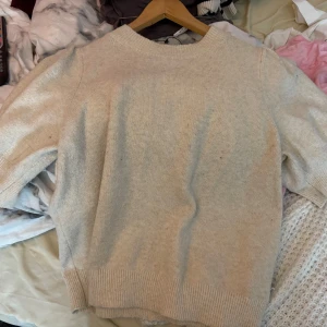 Beige stickad tröja från Vero Moda - Säljer en mysig beige stickad tröja från Vero Moda. Tröjan har en rund hals och ribbade detaljer vid ärmslut och nederkant med puffiga armar. Perfekt för kyligare dagar och en sen sommarkväll. !! De finns ett litet hål på framsidan på tröja!!