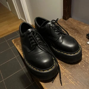 Svarta loafers med snöre  från Dr. Martens - Snygga svarta Dr. Martens skor med klassisk gul söm runt sulan. Skorna har snörning och en robust, grov sula som ger en cool look. Perfekta för att ge din outfit en edgy touch. Köpte för 1600 kr