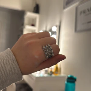 Silvrig ring med nitar - Cool ring i silver med nitar som ger en edgy look. Perfekt för att ge din outfit en tuff touch. Ringen har en bred design och är lätt att matcha med andra accessoarer. Ringen är från Ekblad
