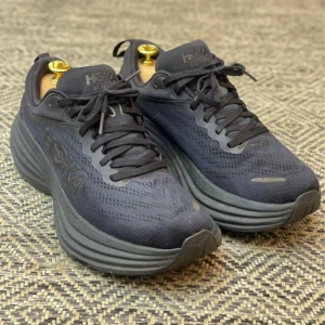 Hoka skor - Snygga svarta sneakers från Hoka med en robust sula och snörning. Perfekta för både träning och vardag. Skorna har en modern design med Hoka-loggan på sidan.