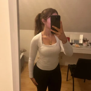 Vit långärmad topp - Säljer en stilren vit långärmad topp med en rund halsringning. Perfekt för lager-på-lager eller att bära som den är. Toppen har en tight passform som framhäver figuren.