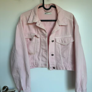 Ljusrosa jeansjacka - Säljer en ljusrosa jeansjacka från H&M. Jackan har en croppad design med knappar framtill och två bröstfickor med lock. Perfekt för vår och sommar! XS