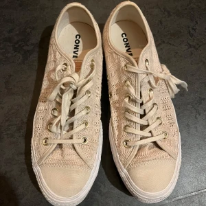 Beige sneakers från Converse - Säljer ett par snygga beige Converse sneakers med stickad design och klassisk snörning. Skorna har en vit sula med Converse All Star-logga på baksidan. Perfekta för en avslappnad stil. Vid fler frågor hör gärna av er!!