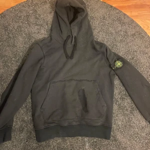 Svart hoodie från Stone Island - Säljer en svart hoodie från Stone Island med klassisk logga på ärmen. Osäker på äktenheten därav priset! Skick 8/10! Vid fler funderingar är det bara att höra av sig! 