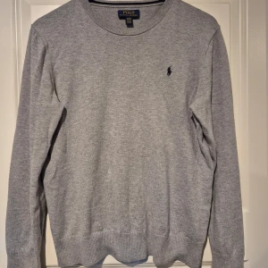 Grå tröja från Polo Ralph Lauren - Finstickad grå tröja från Polo Ralph Lauren. Broderad logga på bröstet. Ungdom XL vilket motsvarar vuxen S. Vid eventuella frågor eller funderingar är det bara att höra av sig.