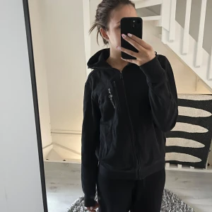 Svart sweatshirt från Sail Racing - Säljer en svart sweatshirt från Sail Racing med dragkedja och luva. Bra skick💕