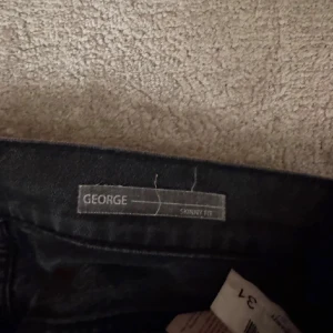 Svarta dondup jeans   - Snygga svarta jeans från dondup i modellen George och storlek 31. De har en klassisk femficksdesign och är perfekta för en stilren look. Passar bra till både vardag och mer uppklädda tillfällen. De är uppsydda en eller två cm