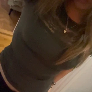 Olivgrön topp med spetsdetaljer - Säljer en olivgrön topp med spetsdetaljer över bröstet och axlarna. Toppen har korta ärmar och en rund halsringning🩷