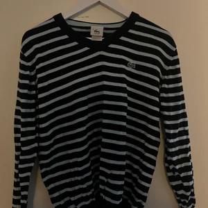 Tröja Lacoste  - En turkos- och mariblårandig finstickad tröja från Lacoste. Den är i storlek 4 men jag skulle säga att den är som S/M. Helt okej använd, men den är i ett jättefint skick. Köparen står för frakten! 