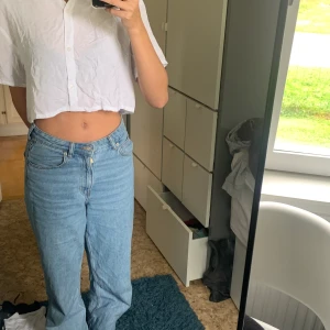 Cropped T-shirt med krage  - En cropped T-shirt i väldigt lätt material som flyger i vinden. Den har en krage och knappar. 