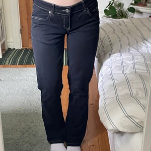 Lågmidjade jeans - Svarta lågmidjade jeans med beiga sömmar. Lite slitet på bakfickorna då det har varit färgade sömmar där tidigare som tagits bort.