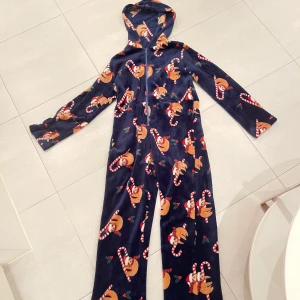 Juljumpsuit  - Säljer denna söta dress med gulligt julmönster! Endast använd en gång. Superskön och bra luva.