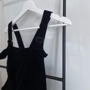 En hängsle klänning i svart Manchester tyg från England