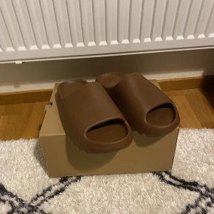 Yeezy Slides Flax - Säljer min helt oanvända äkta Adidas Yeezy Slides Flax i storlek EU 46 (små i storleken). Köpta från SNS, kommer med kartong, kvitto och allt. Skriv privat för mer info! Pris går att diskutera!