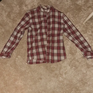 Röd, vit rutig skjorta - Jag säljer denna på grund av att den här blivit för liten för mig men den är i bra skick. Köparen står för frakt