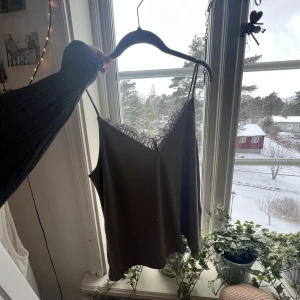 Linne - Ett mörkt grönt linne med spets fram och bak, säljer för att de ej kommer till användning!