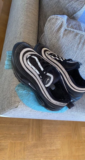 Nike Air Max 97 - Ett par Nike air max 97:or i nästan nytt skick. Svarta med reflex på. Köpta för 2 år sen ca men endast använda 2-3 gånger. Nypris 1500kr