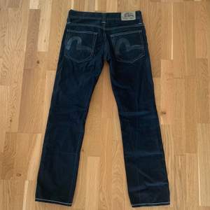 Svarta Evisu jeans som passar storlek 30/32. Utmärkt skick.  Mått:  Midja 40 cm Inre söm 79 cm Benöppning 19 cm Hela yttersidan från midja till benöppning 100 cm