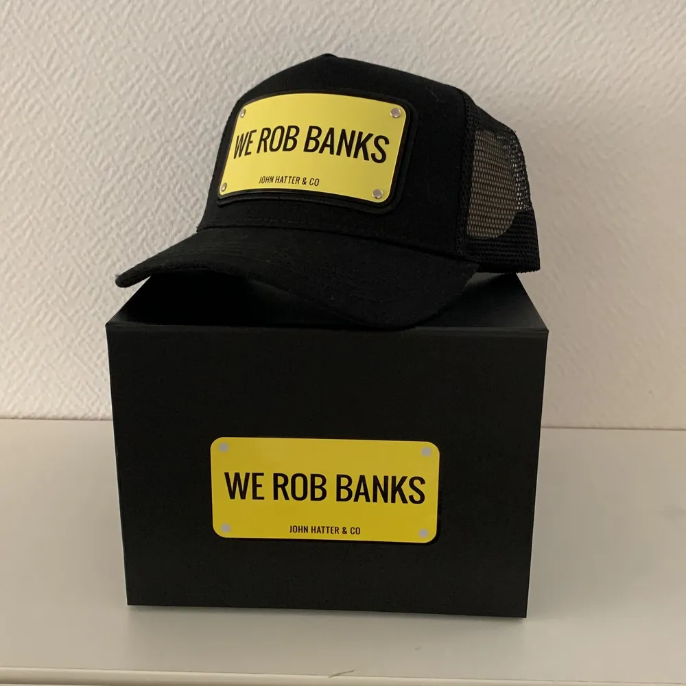 En keps från ”John Hatter & co”. Den är oanvänd, inga skador eller skavanker. Budskapet på är ”WE ROB BANKS”. Köparen står för frakt.. Accessoarer.