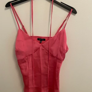 Rosa Topp - En rosa satintopp med tillhörande snöre som man kan knyta i midjan. Funkar perfekt till fest. 