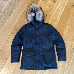 J Lindeberg Dunjacka med pälskrage XL - Fin och varm dunjacka från J Lindeberg. Köpt för några år sedan men sparsamt använd på grund av lite för liten. Jag är 197 cm och normalbyggd. En knapp saknas på ena fickan. Nypris 5000 kr. 