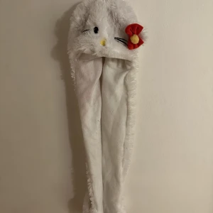 Hello Kitty mössa  - Hello Kitty mössa med långa ”armar” med små fickor längst ner som man kan använda som vantar