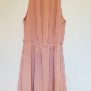 Rosa klänning - Gammelrosa sommarklänning strl 34. Chiffongliknande tyg. Knäppes med krok, har också delvis/diskret öppen rygg över skuldrorna, se bild. Går ungefär strax ovanför knäna på mig som är 163cm. Endast använd ett fåtal gånger, nyskick. Pris exkl frakt.