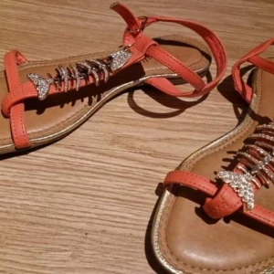 Strl 37 coral bellissimo  - Sandaler stl 37, vacker korallfärg, fiskmotiv med cubic zirconia.  Perfekt skick, prövad en gång   vissa skor behöver rengöras, de låg i en påse med andra skor, så de kan vara smutsiga eller dammiga, mycket bra skick, perfekt skick eller nya skor, storlek