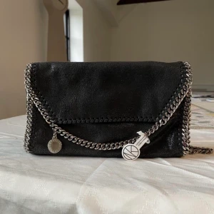 Stella mc väska - Hej❣️Intressekoll på min stella mc väska. Den är i ny skick.  Såklart äkta, väskan är köpt för 7000. Skulle helst byta mot modellen Falabella Fold-Over Tote Bag mini svart med guldkedja❤️ Hör av dig om du vill köpa eller byta🫶 2 första bilderna är lånade❣️
