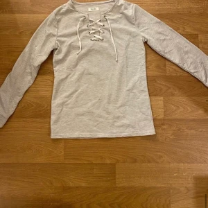 Långärmad tröja - Ljusgrå långärmad tröja med snörning, vet inte vad märket är, storlek S 