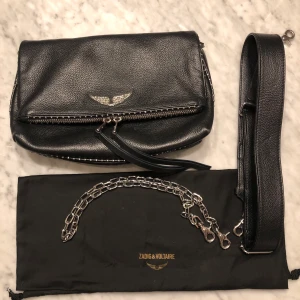 Zadig & Voltaire väska (större modell) - Zadig & Voltaire väska i modellen ”ROCKY GRAINED LEATHER + STUDS”. Köpt för ca 1 år sedan. Väskan är i god skick men finns små knappt synliga defekter på ena främre dragkedjan och på axelremsöglorna. Men inget som påverkar funktionellt. Kvitto finns😇