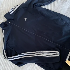 Adidas  - Detta är en XL Adidas. Det är som en tunn oversize tröja? Skulle inte kalla det en jacka. Väldigt bekväm, skön och använd fåtal gånger. Jag är en S/M i vanliga kläder, och denna faller oversizead och snyggt  :-)  Pris kan diskuteras vid snabbt köp