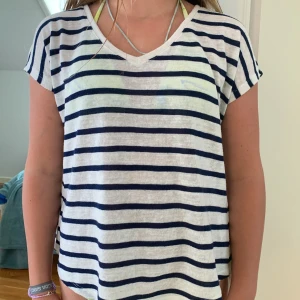 Randig t-shirt med släp - Detta är en randig t-shirt med ett litet släp där bak. Den är använd många gånger men är i gott skick. Den är i storleken Xs och säljs för 150kr + frakt