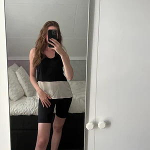 Lindex | Blus med låg polokrage - Svart blus med låg polokrage, och satin-liknande material på nederdelen av blusen i färgen champagne. 