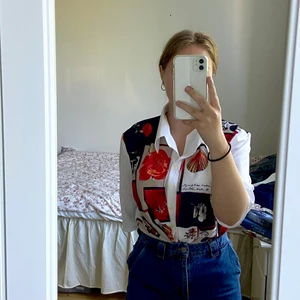 Cool vintage skjorta - Mönstrad vintage-skjorta. Ryggen är marinblå. Framsidan är vit med rött och blått mönster. Mönstret är av olika blommor, snäckor, text och annat. Vill ni ha fler bilder så är det bara att kontakta mig :)