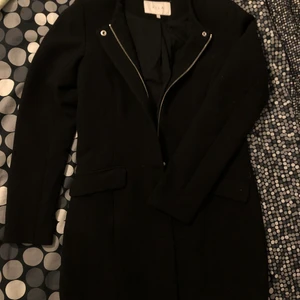 Kappa VILA - En svart kappa från VILA. Snygga sömmar framtill och baktill. Dragledja ur funktion men knapprna framtill fungerar. Slutar en bit över rumpan för mig som är 166 cm. 