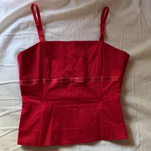 Rött linne med rosett - Ett korsett aktigt linne som jag köpte i Ystad av en väldigt trevlig dam. Den har justerbara axelband!!!🙀 Du står för frakten 👍🏻