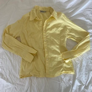 Gul figursydd skjorta - Figursydd skjorta i en superfin gul färg. Köpt second hand men ursprungligen från Indiska. Den är i ett stretchigt material vilket gör att den sitter tight och snyggt! ☀️ Skriv för fler frågor 