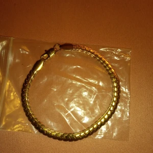 Armband Guldfärgat med lås mönstrad . - Vackert armband Guldfärgat med lås mönstrad 21 cm långt..Ej Guld .hämtas i Skene alt skickas o fraktfritt o Swishbetalning tillämpas .