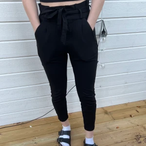 Paperbag byxor strl XS - Hög midja, ankellängd paperbag byxor från Vero Moda. Köpta för kanske 2 år sedan för 450kr, använda fåtal gånger. Väldigt stretchiga byxor. ”Modellen ” på bilden är runt 165. Säljs pågrund av att dom ej användas. Du står för frakten själv. 