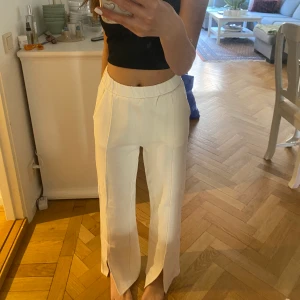 Vita byxor GinaTricot  - Krämvita byxor från GinaTricot med slits vid benen. Har små fläckar vid ena benet (bild 2) är osäker på om de går bort. Kan mötas upp eller frakta.