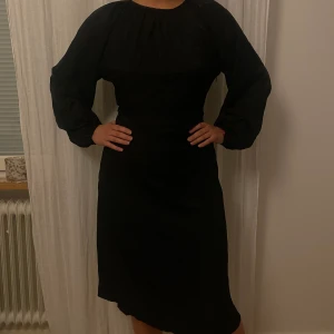 Svart stilren midiklänning (nyskick) - Svart midiklänning med knyt i midjan. Stilren och bekväm.   Nyskick - prislappen kvar 