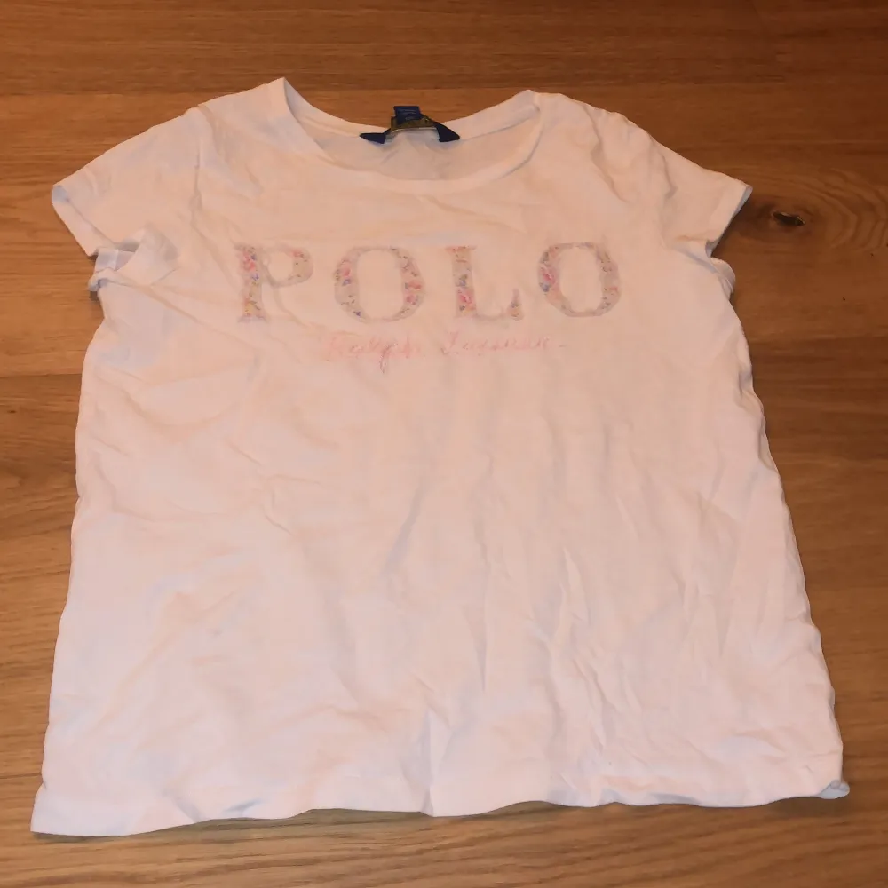 Vit tröja där det står Polo på. T-shirts.