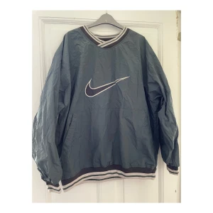 Nike anorak  - En grön anorak från Nike! Överlag i bra skick förutom det lilla hålet. Hålet är vid skulderbladet.  Storlek XL, men passar även en L