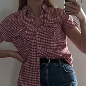 Röd-vitrutig skjorta från H&M - Jättefin röd-vitrutig kortärmad skjorta från H&M i bra skick. Använd endast ett fåtal gånger. Gjord i 100% bomull. Storlek 44, men upplever den som storlek 38/40. Något insydd i midjan. 120kr inklusive frakt<3