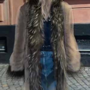 Penny lane jacka/coat - Jättefin brun fodrad kappa i pennylane stil. Pälskrage. Har ett bälte man kan knyta runt för att stänga men har även små krokar innuti så man kan stänga den utan bälte. Perfekt till vintern! Står storlek 40 men passar alla storlekar.