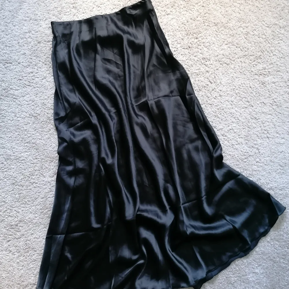 Shiny A-line skirt. Elastic band and zipper closing. . Kjolar.