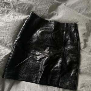 En jättefin kjol från Asos tall i strl 38. Använd en gång och i nyskick.  Svart/brun färg, liten slits framtill. 
