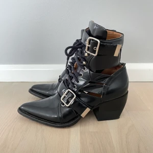 Chloe Rylee boots 39,5 - Äkta Chloe Rylee leather ankle boots i svart.Storlek 39,5 Välanvända men i väldigt bra skick trots en spricka på baksidan (bild finns) som kan åtgärdas hos en skomakare.Dustbagen har jag inte kvar men certifikat finns! Nypris ca 11000kr.   